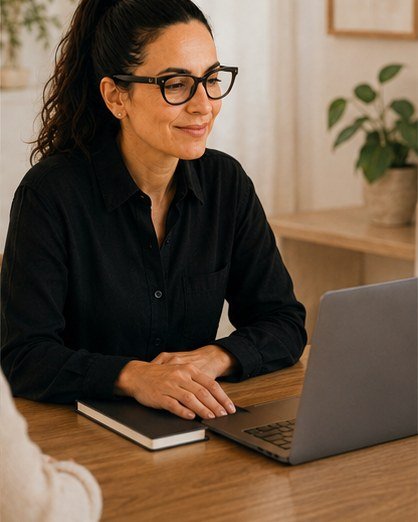 Mujer sonriendo durante una sesión online RESET, con portátil y cuaderno